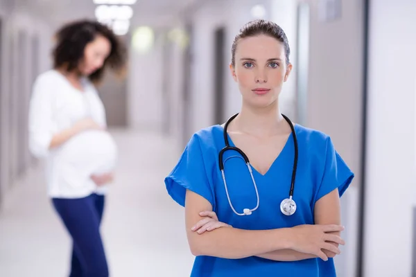 Porträt einer Ärztin, die mit verschränkten Armen im Gang steht — Stockfoto