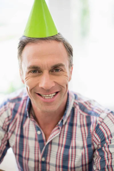 Hombre sonriente con sombrero de fiesta en casa —  Fotos de Stock