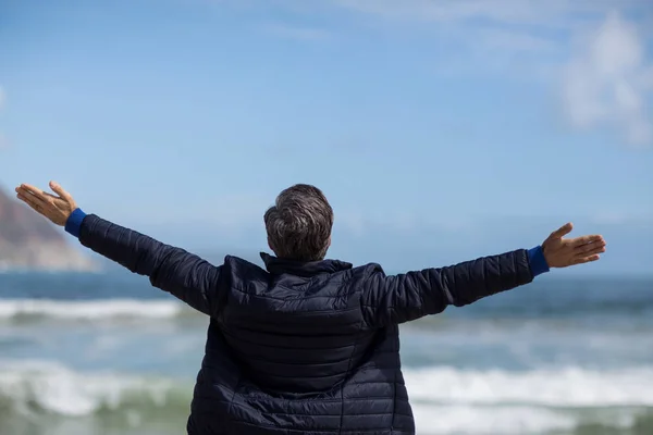 Reifer Mann mit ausgestreckten Armen am Strand — Stockfoto