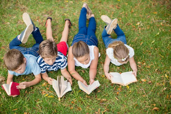 Τα παιδιά ξαπλωμένος στο γρασίδι και ανάγνωση βιβλίων — Φωτογραφία Αρχείου