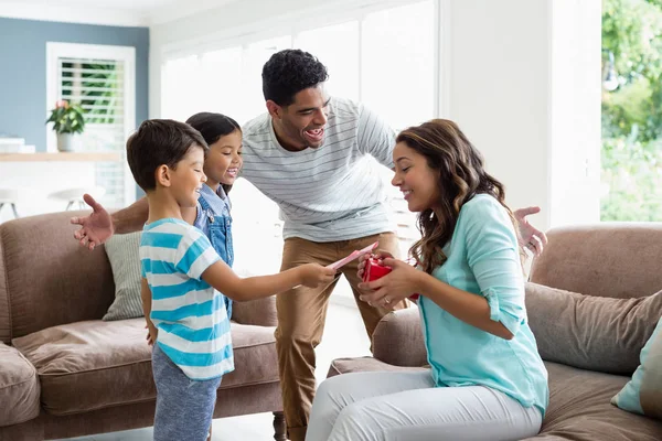 Mother receiving a gift from his kids and husband in living room — Stock Photo, Image