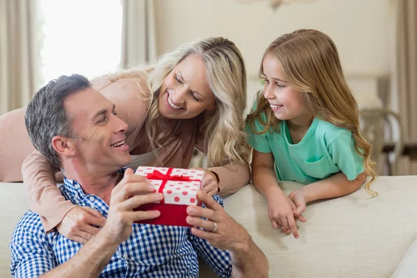 Vater erhält Geschenk von Tochter und Frau im Wohnzimmer — Stockfoto