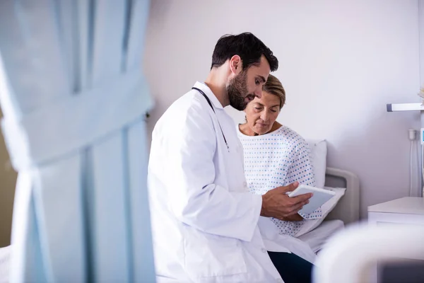 Médico masculino mostrando comprimido digital para paciente sênior do sexo feminino na enfermaria — Fotografia de Stock