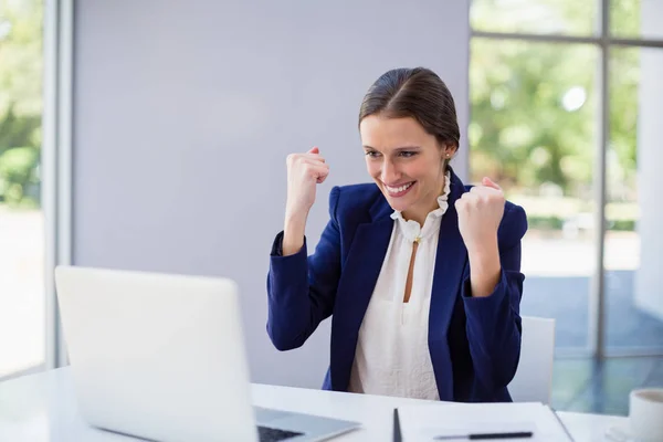 Glad affärskvinna med laptop på skrivbord — Stockfoto