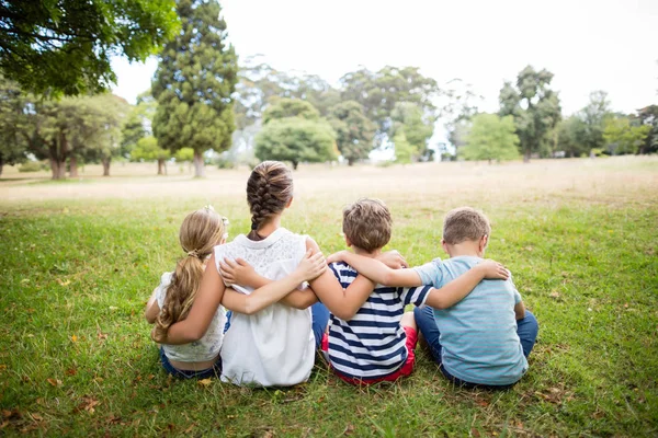 Crianças sentadas juntas no parque — Fotografia de Stock