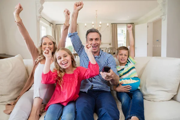 Family watching soccer match on television in living room — Stock Photo, Image
