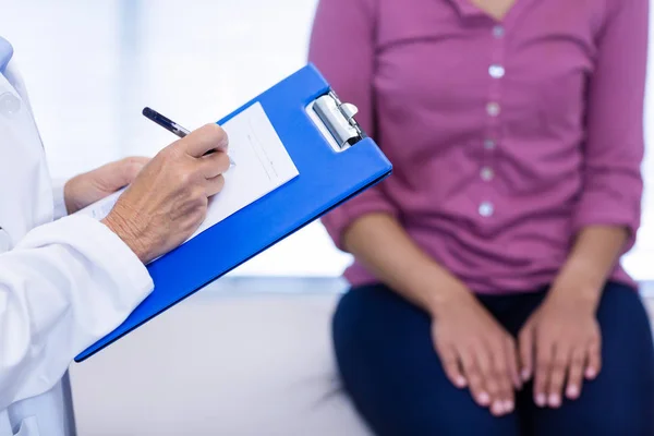 Doctor escribiendo en portapapeles en la clínica —  Fotos de Stock