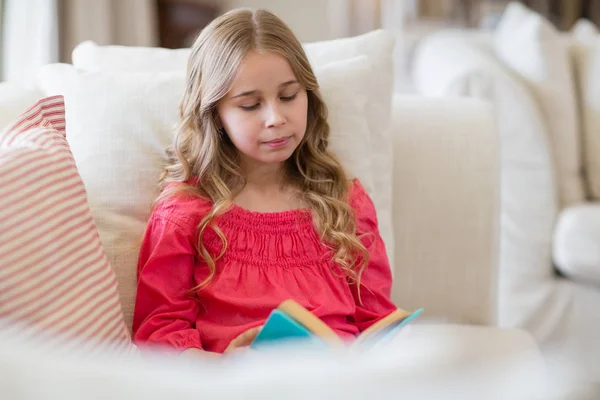Dívka s knihou na pohovce v obývacím pokoji — Stock fotografie