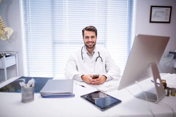 Portrét mužské lékař sedí u stolu机に座っている男性医師の肖像画 — Stock fotografie
