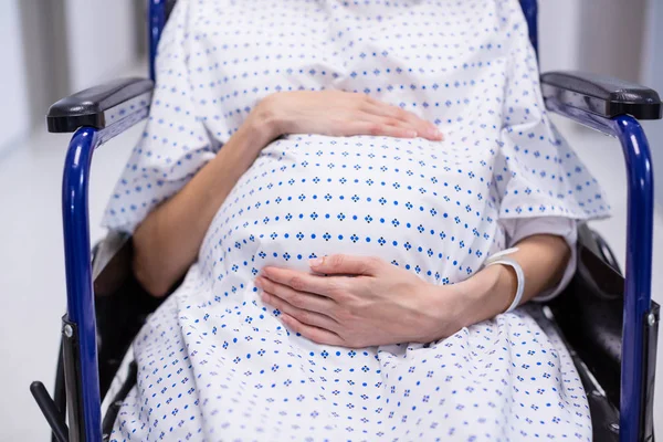 Mid section of pregnant woman sitting on wheelchair — Stock Photo, Image