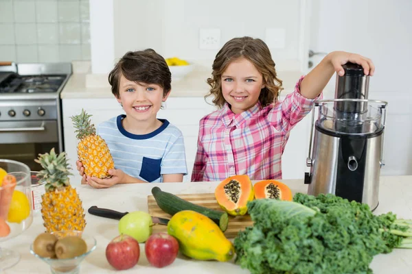 Bambini sorridenti che preparano un succo in cucina — Foto Stock