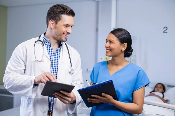 Médecin et infirmière souriants utilisant la tablette numérique et presse-papiers — Photo