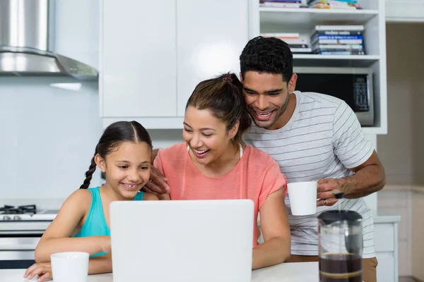 Los padres y la hija usando el ordenador portátil en la cocina en casa —  Fotos de Stock