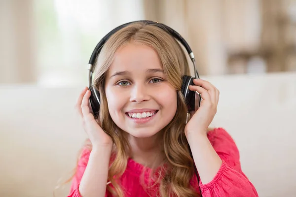 Uśmiechający się ładny dziewczyna słuchanie muzyki na słuchawkach w salonie w domu — Zdjęcie stockowe