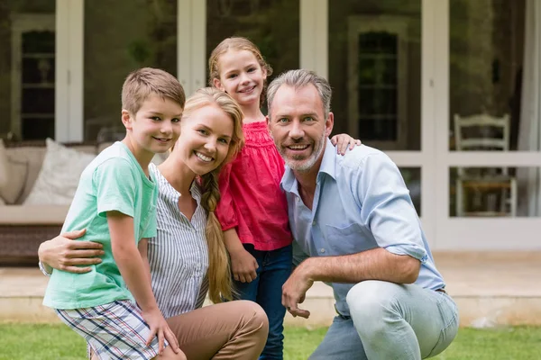 Lycklig familj med arm runt sitter i trädgården — Stockfoto
