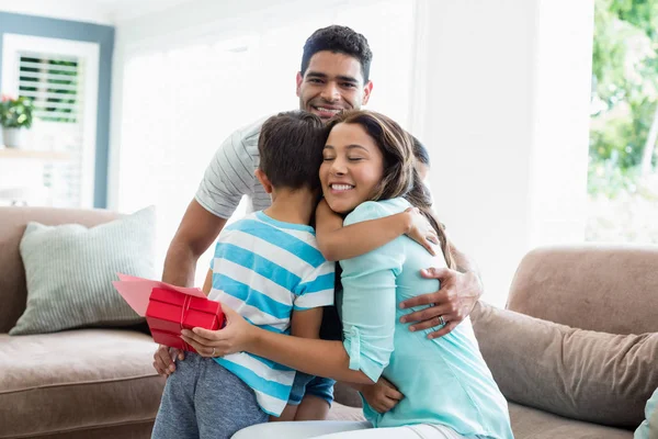 Mère recevant un cadeau de ses enfants et de son mari dans le salon — Photo