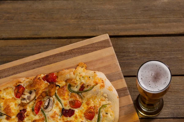 Heerlijke pizza geserveerd op een houten bord met een glas bier — Stockfoto