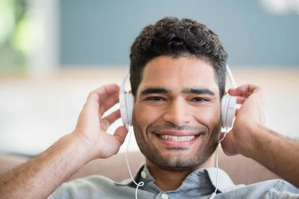 Homem ouvindo música em fones de ouvido na sala de estar em casa — Fotografia de Stock