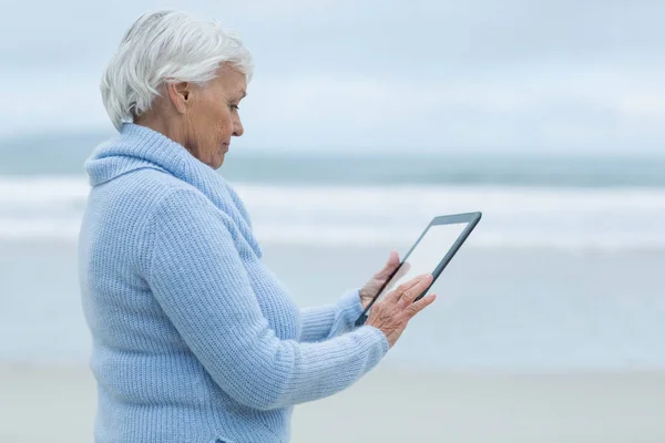 Donna anziana utilizzando tavolo digitale sulla spiaggia — Foto Stock