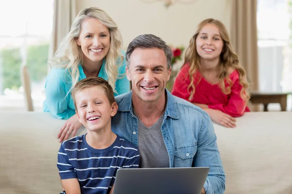 Πορτρέτο του χαμογελώντας τους γονείς και τα παιδιά με το φορητό υπολογιστή στο σαλόνι — Φωτογραφία Αρχείου