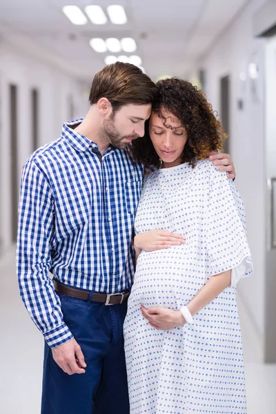 Man tröstande gravid kvinna i korridor — Stockfoto