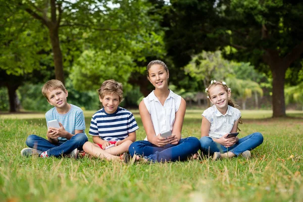 Niños usando teléfono móvil en el parque — Foto de Stock