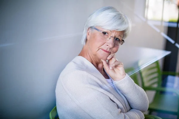 Nachdenkliche Seniorin sitzt auf Stuhl — Stockfoto