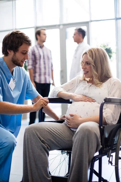 Erkek doktor tekerlekli sandalyede hamile kadın konuşuyor — Stok fotoğraf