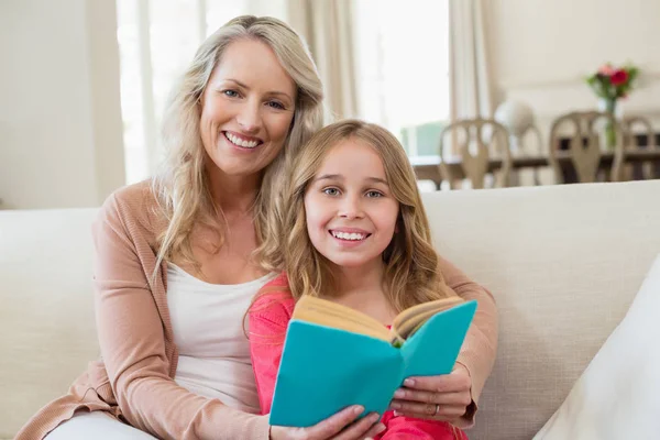 Mother and daughter reading a novel on the couch — Stock Photo, Image