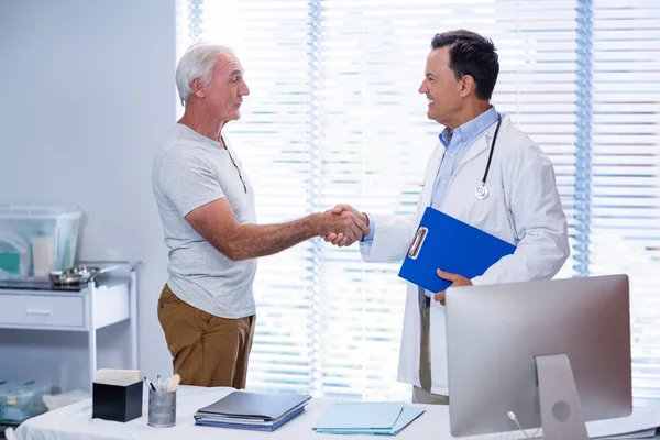 Doctor shaking hands with senior man — Stock Photo, Image