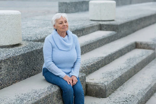 Thoughtful senior woman sitting on the steps — Stock Photo, Image