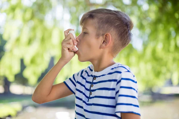 Хлопчик використовує інгалятор астми в парку — стокове фото