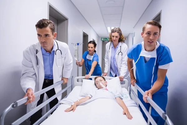 Doctors pushing emergency stretcher bed in corridor — Stock Photo, Image