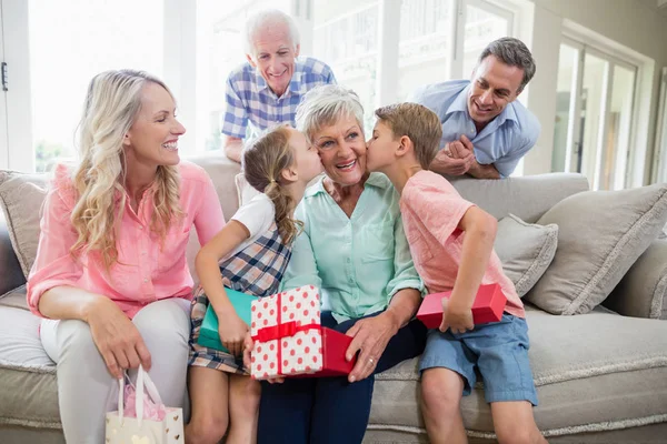 Grootmoeder een kus ontvangen hun kleinkinderen in woonkamer — Stockfoto