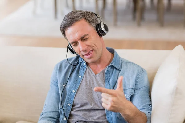 Hombre escuchando música en auriculares en la sala de estar en casa —  Fotos de Stock