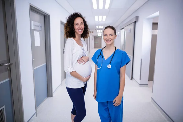 Portrét lékaře a těhotných ženách postavení v chodbě — Stock fotografie