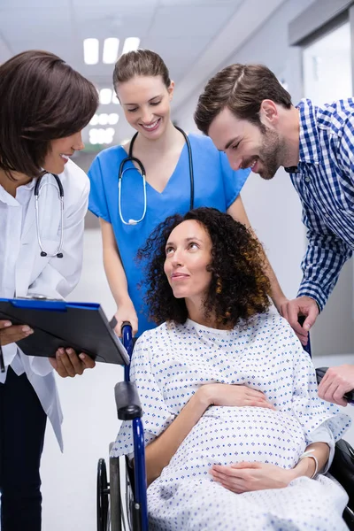 Médico interactuando con la mujer embarazada en el pasillo —  Fotos de Stock