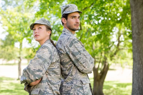 Casal militar de pé com braços cruzados no parque — Fotografia de Stock