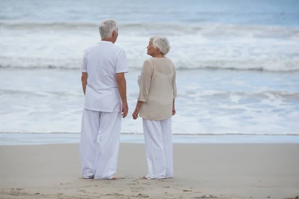 Старшая пара взаимодействует друг с другом на пляже — стоковое фото