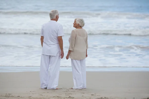 Couple sénior interagissant les uns avec les autres sur la plage — Photo