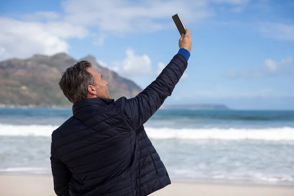 Érett ember vesz egy selfie-ból mozgatható telefon, a strandon — Stock Fotó