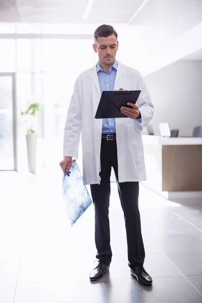 Doctor standing with clipboard in corridor — Stock Photo, Image