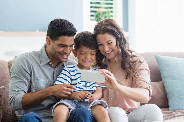 Padres e hijo revisando fotos en el teléfono móvil —  Fotos de Stock