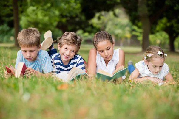 Дети лежат на траве и читают книги — стоковое фото