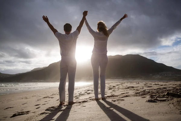 Casal de pé com as mãos dadas na praia — Fotografia de Stock