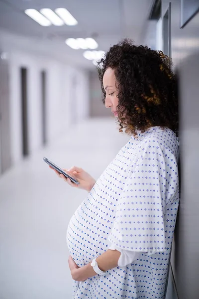 Mulher grávida usando telefone celular no corredor — Fotografia de Stock