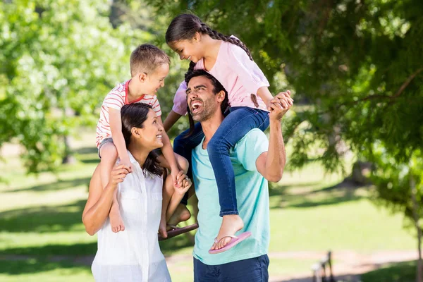 Föräldrar bär sina barn på axeln i park — Stockfoto