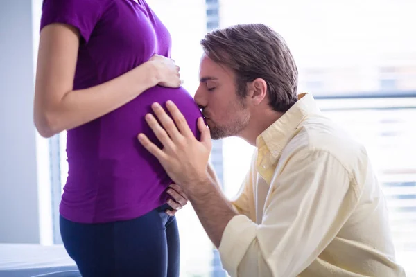 Mannen som kysser gravid kvinnas mage i församling — Stockfoto