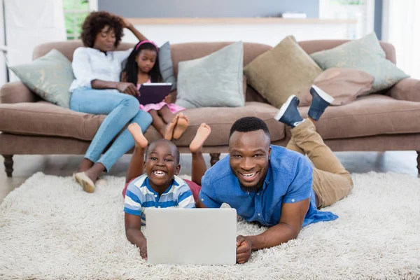 父亲和女儿躺在地毯上和在家里使用笔记本电脑 — 图库照片
