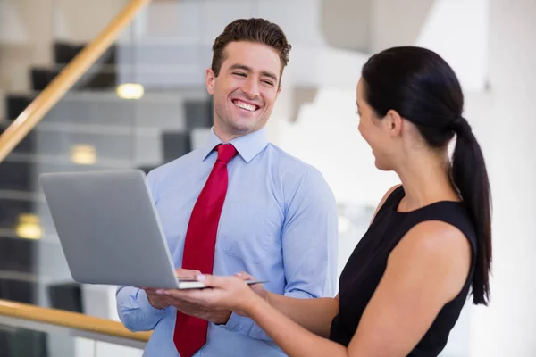 Företagsledare håller en laptop och skrattar — Stockfoto